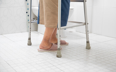 Elderly woman using walker in toilet for safety.