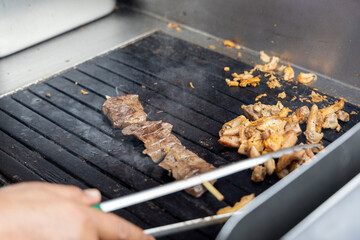 A person is cooking anticuchos on a grill