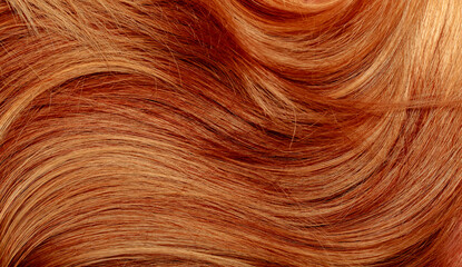 Red hair close-up as a background. Women's long orange hair. Beautifully styled wavy shiny curls....