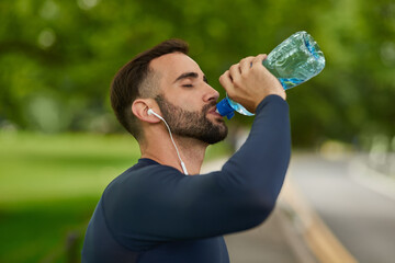 Man, music or drinking water in park for fitness, hydration or thirsty in exercise. Rest, bottle or...