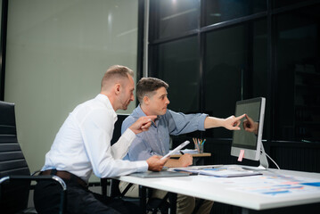 Two business workers talking on the smartphone and using laptop