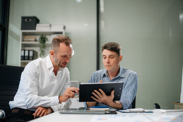 Two business workers talking on the smartphone and using laptop
