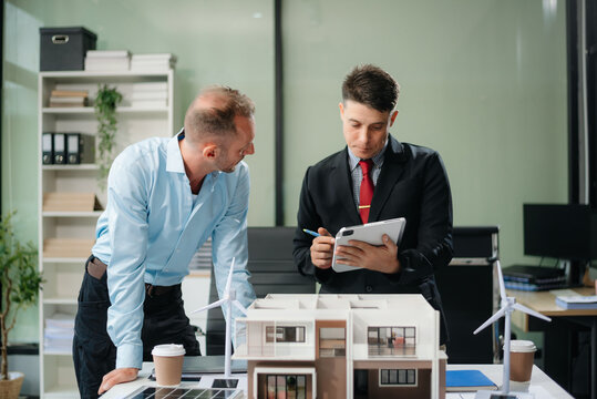 Meeting of architects, designers, and developers creating innovative, sustainable housing projects using building models and digital tools.