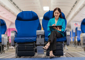 Businesswoman on Airplane: A professional woman in a teal blazer works on her tablet while seated in the cabin of an airplane. Her confident posture and focused expression suggest a successful journey