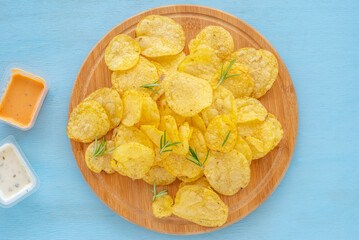 Potato chips in coconut bowl over blue background..