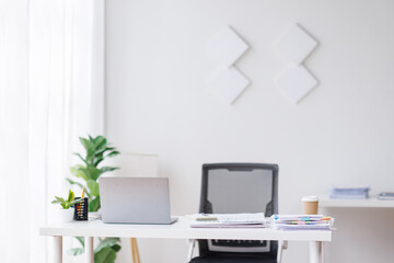 Laptop Computer, notebook, and eyeglasses sitting on a desk in a large open plan office space after working hours
