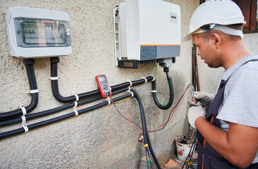 Man electrician installing solar panel system. Technician in helmet and gloves making electrical...