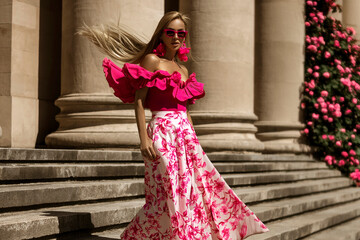 Elegant, stylish woman in pink floral dress and sexy high heels is sensually walking in the city on...