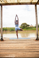 A beautiful young black woman practicing yoga outdoors in the countryside