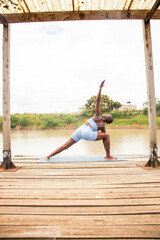 A beautiful young black woman practicing yoga outdoors in the countryside