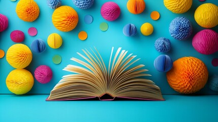 An open book rests on a bright blue surface surrounded by colorful decorative spheres