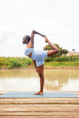 A beautiful young black woman practicing yoga outdoors in the countryside
