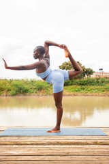 A beautiful young black woman practicing yoga outdoors in the countryside