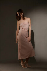 Fototapeta premium Serie of studio photos of female model in elegant beige strapless maxi dress