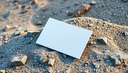 A white business card mockup with a minimalist design, resting on a rocky, sandy surface, mockup for card, mockup for visiting card
