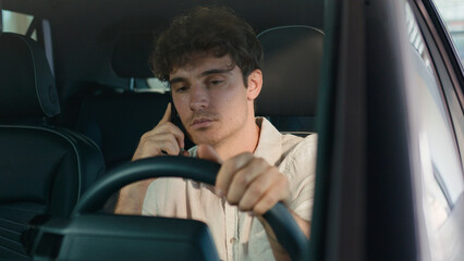 Caucasian business man driver male guy driving new luxury modern electric car talking mobile phone...