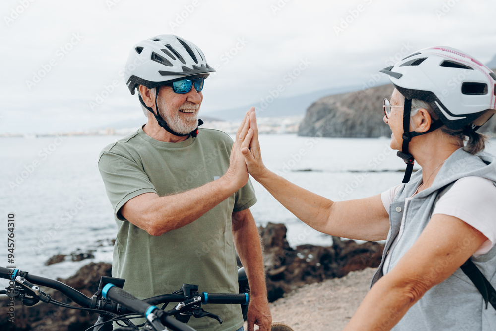 Canvas Prints Couple of two seniors giving five together outdoors having fun with bicycles enjoying nature. Couple of old people building a healthy and fit lifestyle..