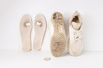 Pair of worn out shoes with visible wear, dirt, and scuffs. Old and heavily used footwear showing signs of damage, including frayed edges, holes, and detached soles. Aged, shabby