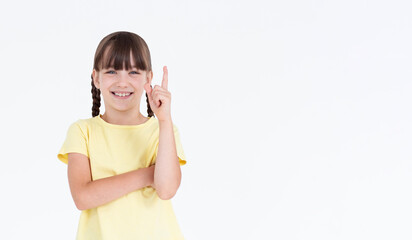 Portrait of smiling girl pointing a great idea, isolated on white background. Beautiful young teenager keeping finger up, looking at camera. Happy cute child have unexpected idea