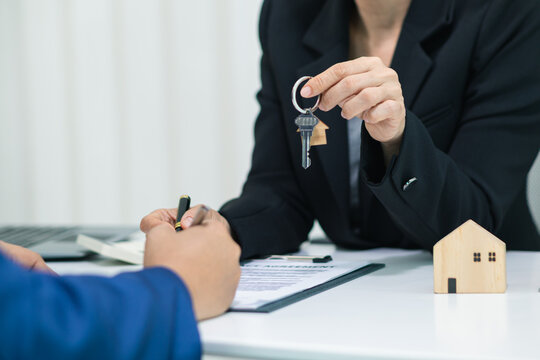 Real estate agent handing over house keys to customer after agreeing to sign sales contract and signing real estate handover contract to customer. Successful real estate sales contract concept