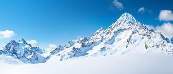 Obraz premium majestic snowy mountain range peak panorama with clear blue sky and fluffy clouds for travel and nature backgrounds.