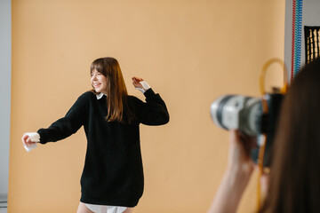 A young female photographer is photographing a model, behind the scenes of a photo session in a...