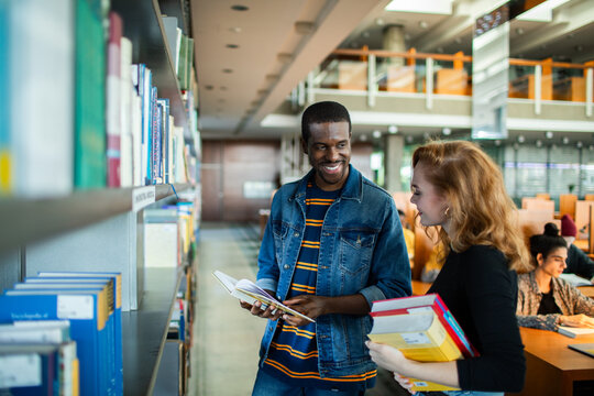Diverse students picking books in college library