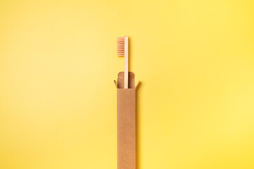 Eco-friendly dental wooden bamboo toothbrushes with cardboard packaging on yellow background. Dental care and health, plastic-free life, zero waste, save the planet. Flat lay top view copy space 