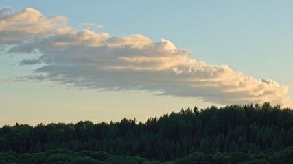 Interesting cloud over the forest at sunset on a summer day.                               