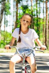 Obraz premium Child riding bicycle. Little kid girl on bicycle along bikeway. Happy cute little girl riding bicycle. Child cycling on bicycle.