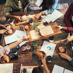 Above, business and people in meeting with food for finance planning, documents and teamwork of financial budget. Staff, meal and coffee with paperwork, graphs and profit stats for accounting at cafe