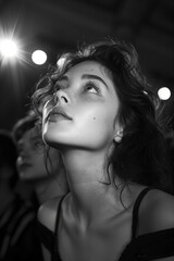 Captivated woman gazing upward in dramatic lighting, black and white artistic portrait