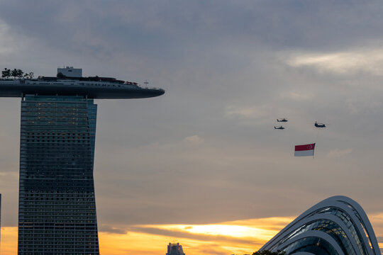 Singapore National Day helicopter hanging Singapore flag flying over the Marina Sands Hotel.
