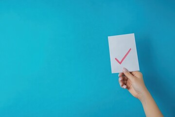 Hand holding a ballot with a check mark on blue background