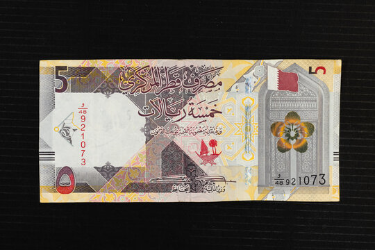 Flag of Qatar, Dreama flower and a gate representing historical Qatari architecture, portrait from Qatar 5 riyals 2020 banknote.
