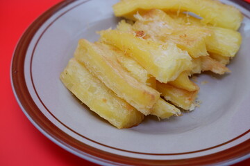 Fried cassava served on a plate. Fried cassava dish isolated on a red background.