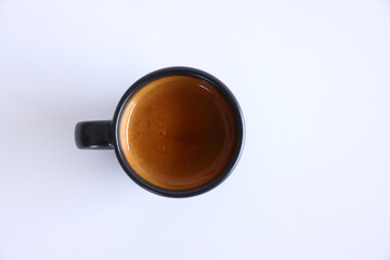 Hand holding a black cup of hot espresso coffee mugs and a cup of espresso coffee with black table in isolate black background
