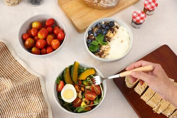 granola yogurt blueberry with salad tomato and bread in white ceramic bolw, isolated on white background.