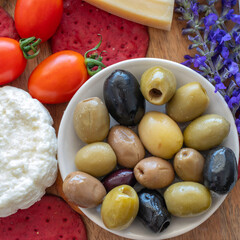 Green and black olives over cheese board.