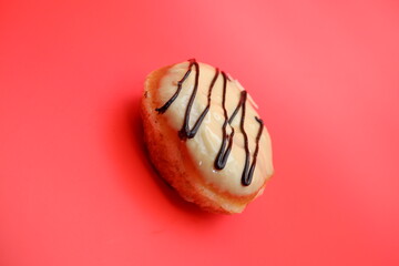 donut cake with white chocolate glaze topping and chocolate spread in zigzag pattern. donut cake isolated on red background.