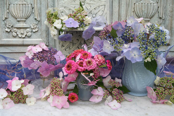 Still life of flowers in vases on a marble table with an ornate carved wooden painted background.