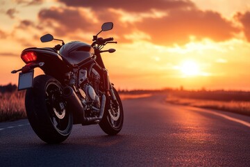 A black motorcycle parked on a road with a sunset in the background.