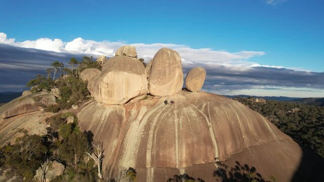Aerial view of granite rock formations and boulders surrounded by trees under a vast sky with clouds, Girraween National Park, Stanthorpe, Queensland, Australia.