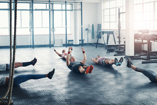 Gym, fitness and group workout on floor for core exercise, wellness or health. Club, abs and people training together with hollow body hold for strong muscle, power or energy with team in sport class
