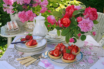 Table set for afternoon tea in a garden in the summer with strawberry cakes still life