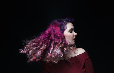 Beautiful stylish woman with pink-purple curly hair on black background.