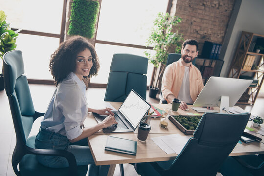 Photo of smart coworkers female man working together look camera sit table comfortable modern office interior indoors workspace