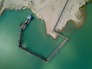 Aerial - drone view of Sand quarry with industrial structures and artificial lake.