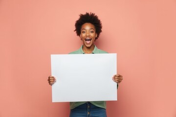Smiling woman holding blank white sign in front of a pink background