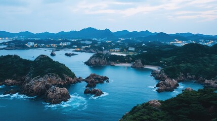 Fototapeta premium The coastal landscape of Hoi An glimmers at night, as waves crash against rocks and illuminated buildings create a warm, inviting atmosphere by the sea